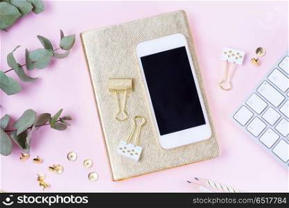 Home office desk with green eucaliptus and modern white phone on pink background. Home office desk with phone. Home office desk with phone