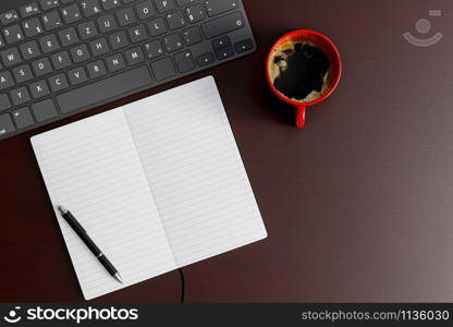 Home office desk with notebook, pen, keyboard and red coffee cup on wood table. Top view flat lay with copy space.