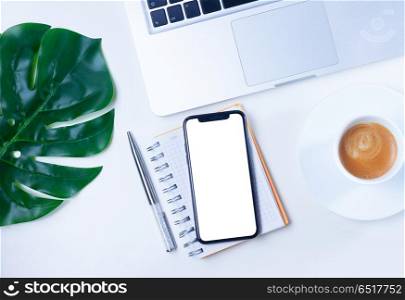 Home office desk with phone. Home office desk with green mostera leaves and modern phone