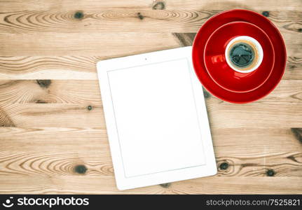 Home office workplace. Digital tablet and cup of coffee on wooden table. Vintage style toned picture