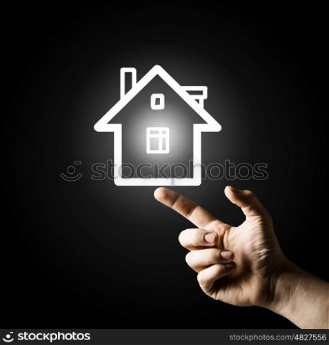 Home on hand. Close up of man hand pointing with finger at house model