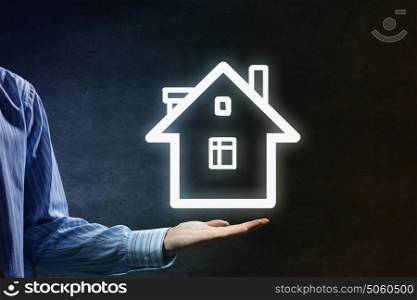 Home on the hand. Hand of businessman showing house sign in palm