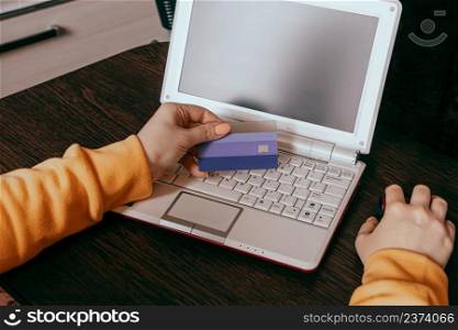 Home online shopping concept. Hand holding a credit card. Woman uses a laptop to shop on the internet. Discounts and sales.. Home online shopping concept. Hand holding credit card. Woman uses laptop to shop on internet. Discounts and sales.