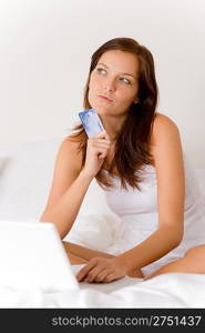 Home online shopping - woman with credit card sitting in white bed