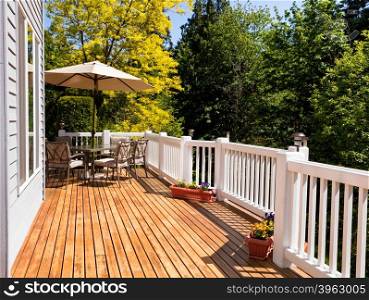 Home outdoor cedar deck with furniture and open umbrella during nice bright day. Horizontal layout.