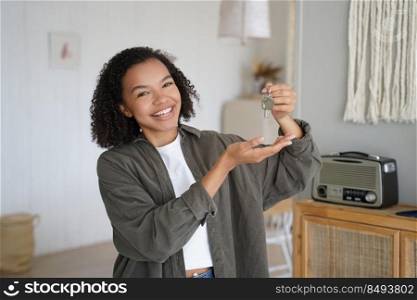 Home ownership. Young african american girl is holding key from new home and showing it. Hispanic teenager gets new apartment key. Mortgage loan and real estate purchase conceptual image.. Home ownership. Young african american girl is holding and showing key from new home.