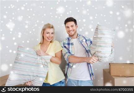 home, people and real estate concept - happy couple pillows moving to new place over snow