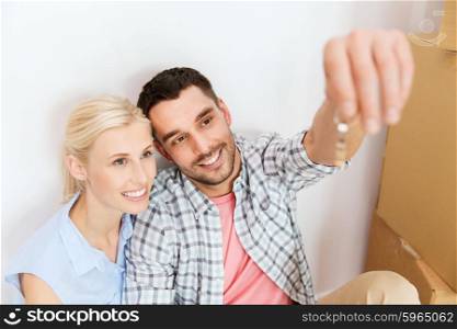 home, people and real estate concept - happy couple with key and cardboard boxes moving to new place
