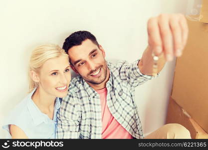 home, people and real estate concept - happy couple with key and cardboard boxes moving to new place