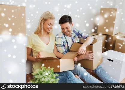 home, people and real estate concept - smiling couple with many cardboard boxes moving to new place over snow