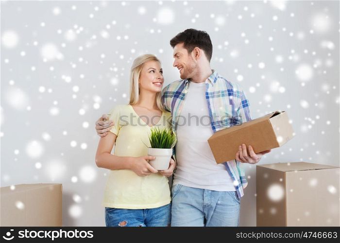 home, people, moving and real estate concept - smiling couple with big cardboard boxes and plant at new place over snow