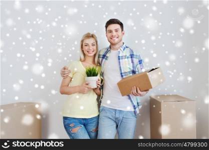 home, people, moving and real estate concept - smiling couple with big cardboard boxes and plant at new place over snow