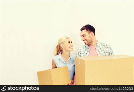 home, people, repair and real estate concept - happy couple holding cardboard boxes and moving to new place