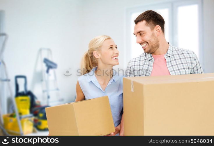 home, people, repair and real estate concept - happy couple holding cardboard boxes and moving to new place