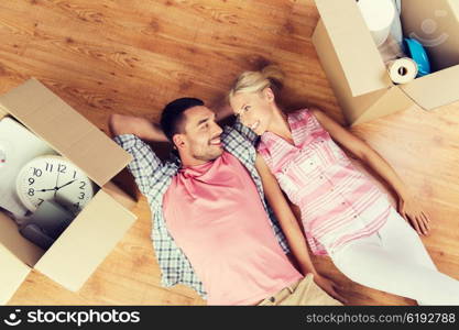 home, people, repair and real estate concept - happy couple with cardboard boxes and stuff lying on floor to new place