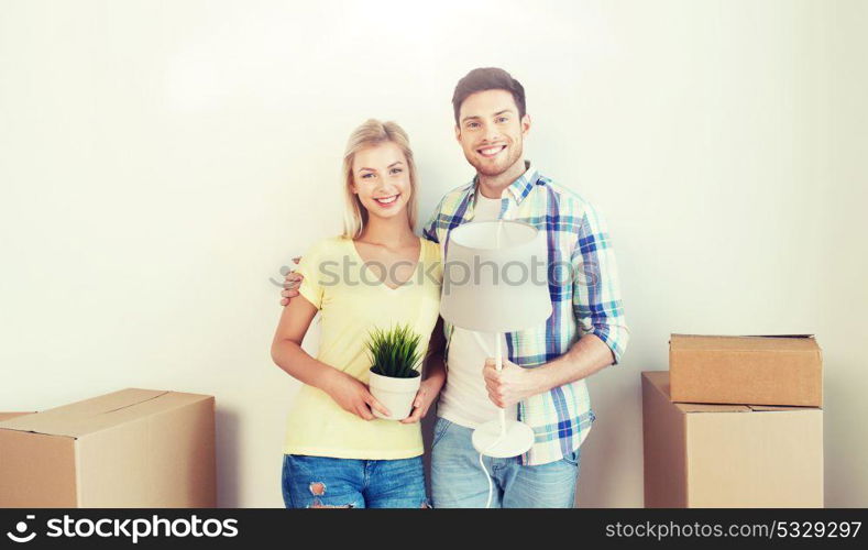 home, people, repair and real estate concept - smiling couple with big cardboard boxes and stuff moving to new place. happy couple with stuff moving to new home