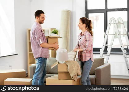 home, people, repair and real estate concept - smiling couple with big cardboard boxes and stuff moving to new place. happy couple with stuff moving to new home