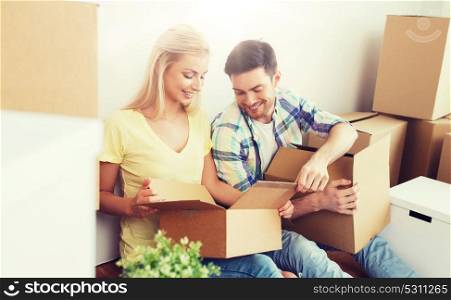 home, people, repair and real estate concept - smiling couple with many cardboard boxes moving to new place. smiling couple with many boxes moving to new home