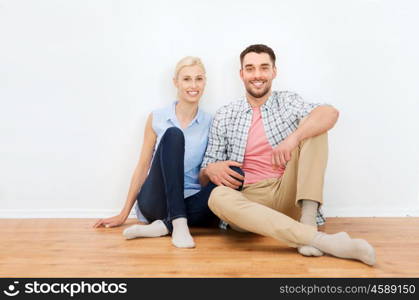 home, people, repair, moving and real estate concept - happy couple of man and woman sitting on floor at new place