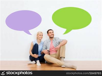 home, people, repair, moving and real estate concept - happy couple of man and woman sitting on floor at new place with empty blank text bubbles
