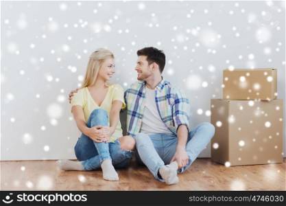 home, people, repair, moving and real estate concept - happy couple with many cardboard boxes sitting on floor at new place over snow