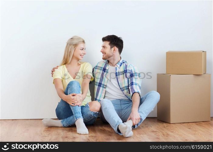 home, people, repair, moving and real estate concept - happy couple with many cardboard boxes sitting on floor at new place