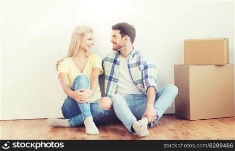 home, people, repair, moving and real estate concept - happy couple with many cardboard boxes sitting on floor at new place. couple with cardboard boxes moving to new home