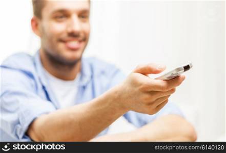 home, people, technology and entertainment concept - close up of man changing channels with tv remote control at home