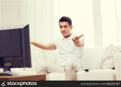 home, people, technology and entertainment concept - disappointed man watching sports on tv and supporting team at home
