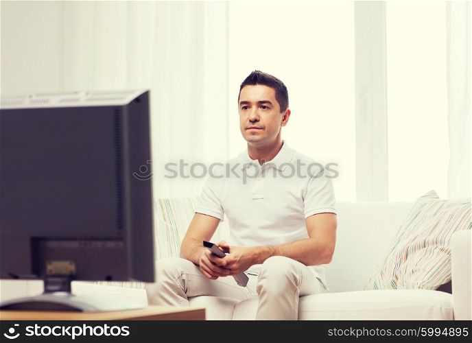home, people, technology and entertainment concept - man with remote control watching tv at home