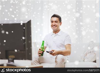 home, people, technology and entertainment concept - smiling man with remote control watching tv and drinking beer at home over snow effect