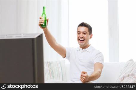 home, people, technology and entertainment concept - smiling man with remote control watching tv and drinking beer at home