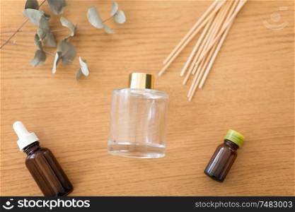 home perfume and aromatherapy concept - aroma reed diffuser, essential oil and branches of eucalyptus populus on wooden table. aroma reed diffuser, essential oil and eucalyptus
