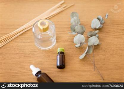 home perfume and aromatherapy concept - aroma reed diffuser, essential oil and branches of eucalyptus populus on wooden table. aroma reed diffuser, essential oil and eucalyptus