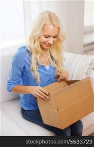 home, post, delivery and happiness concept - smiling young woman opening cardboard box at home
