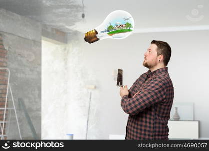 Home renovation and improvement. Man in checked shirt indoors with spatula in hand