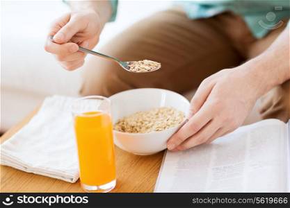 home, rest, news, breakfast and people concept - close up of man reading magazine and eating breakfast at home