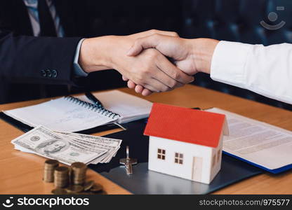 Home sales agents and buyers work on signing new homes and shaking hands.