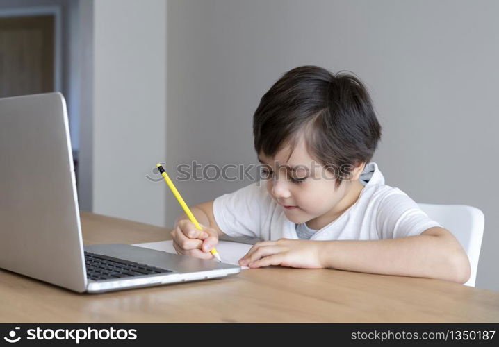 Home school Kid self isolation using laptop for his homework,Child doing using computer notebook searching information on internet during covid lock down, Social Distancing,E-learning online education
