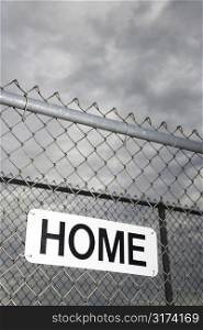 Home sign hanging on metal chain link fence.