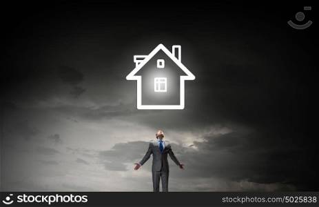 Home symbol. Businessman with hands spread apart and house model above