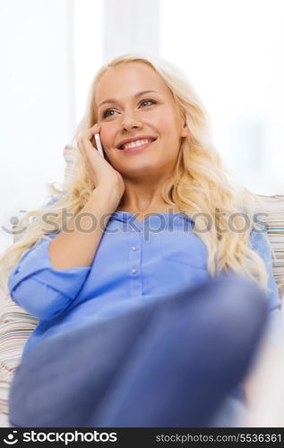 home, technology and communication concept - smiling woman with smartphone lying on couch at home