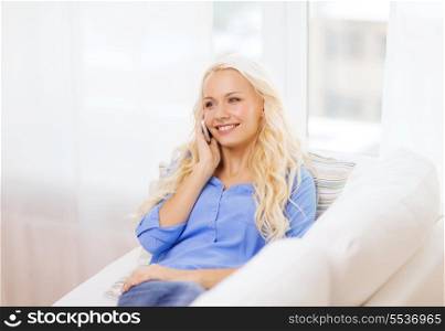 home, technology and communication concept - smiling woman with smartphone lying on couch at home
