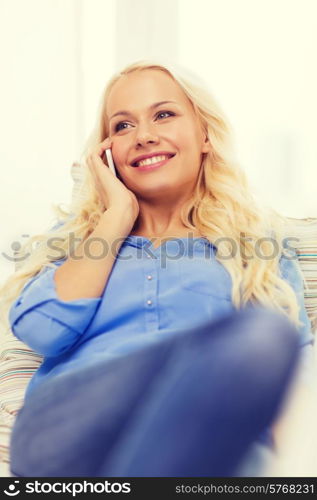 home, technology and communication concept - smiling woman with smartphone lying on couch at home