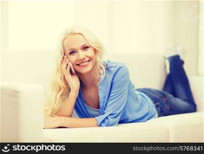 home, technology and communication concept - smiling woman with smartphone lying on couch at home