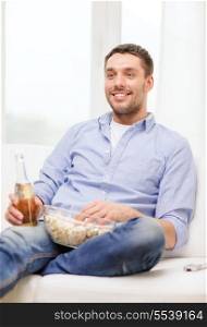 home, technology and entretainment concept - smiling man with beer and popcorn at home