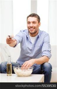 home, technology and entretainment concept - smiling man with beer, popcorn and tv remote control at home