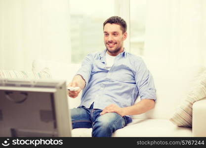 home, technology and entretainment concept - smiling man with tv remote control at home