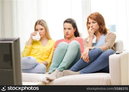 home, technology and friendship concept - three sad teenage girl watching tv at home
