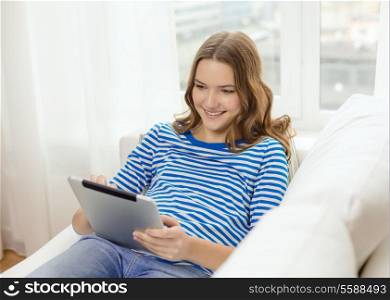 home, technology and internet concept - smiling teenage girl lying on the couch with tablet pc computer at home